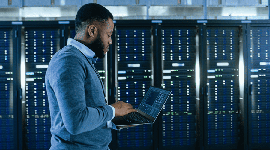 Concept photo of a man working on his computer with mainframes in the background.